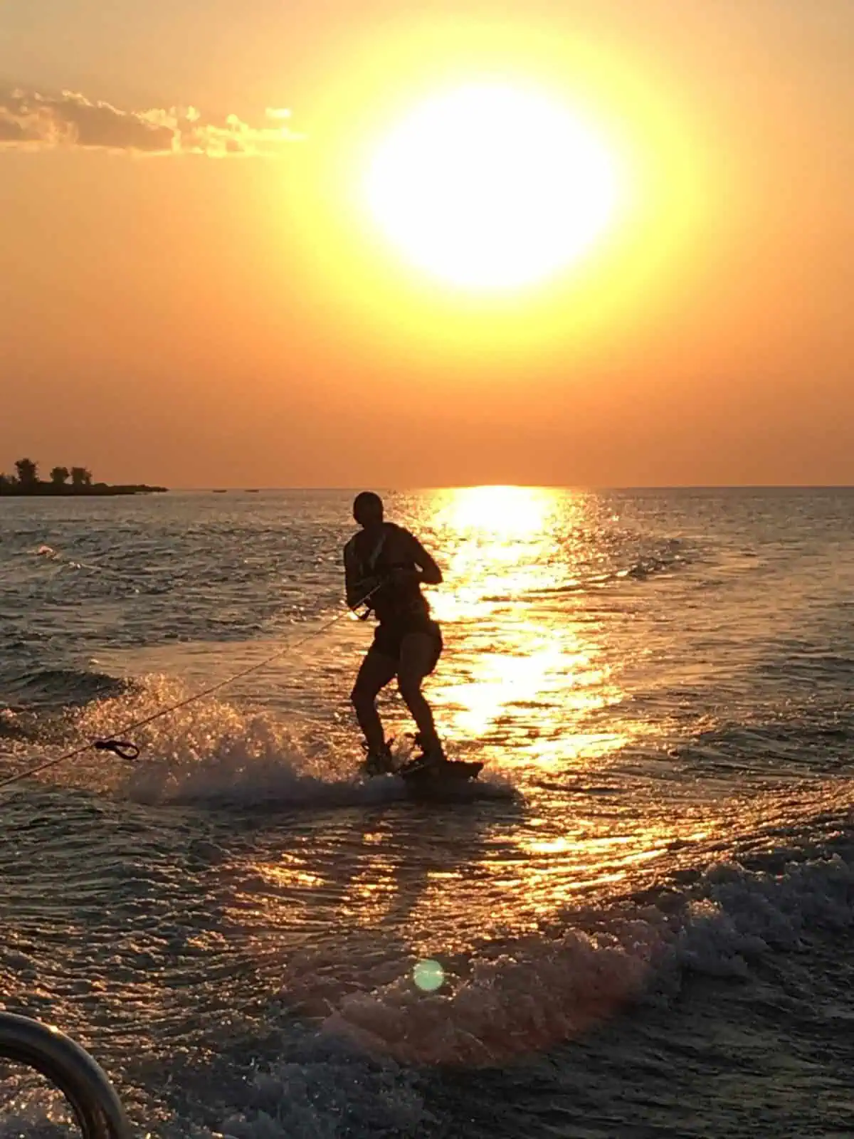 Me wakeboarding on the water at sunset, silhouetted against the setting sun