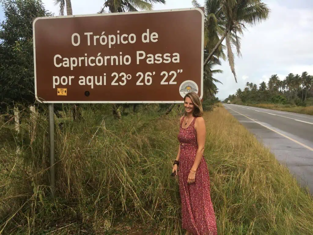 Me standing beside a roadside sign marking the Tropic of Capricorn