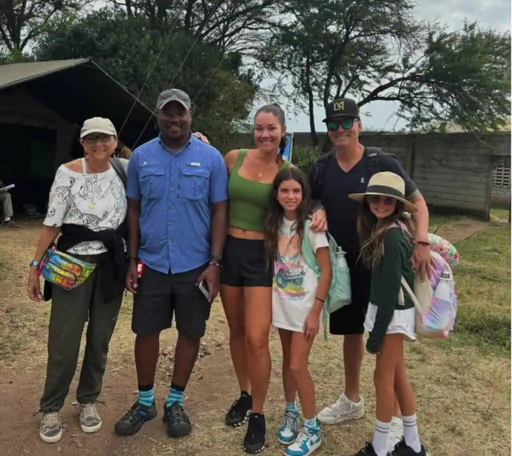 Vibrant group of travelers enjoying an authentic Africa safari experience in a natural outdoor setting with trees and a tent in the background, capturing the spirit of adventure and wildlife exploration.