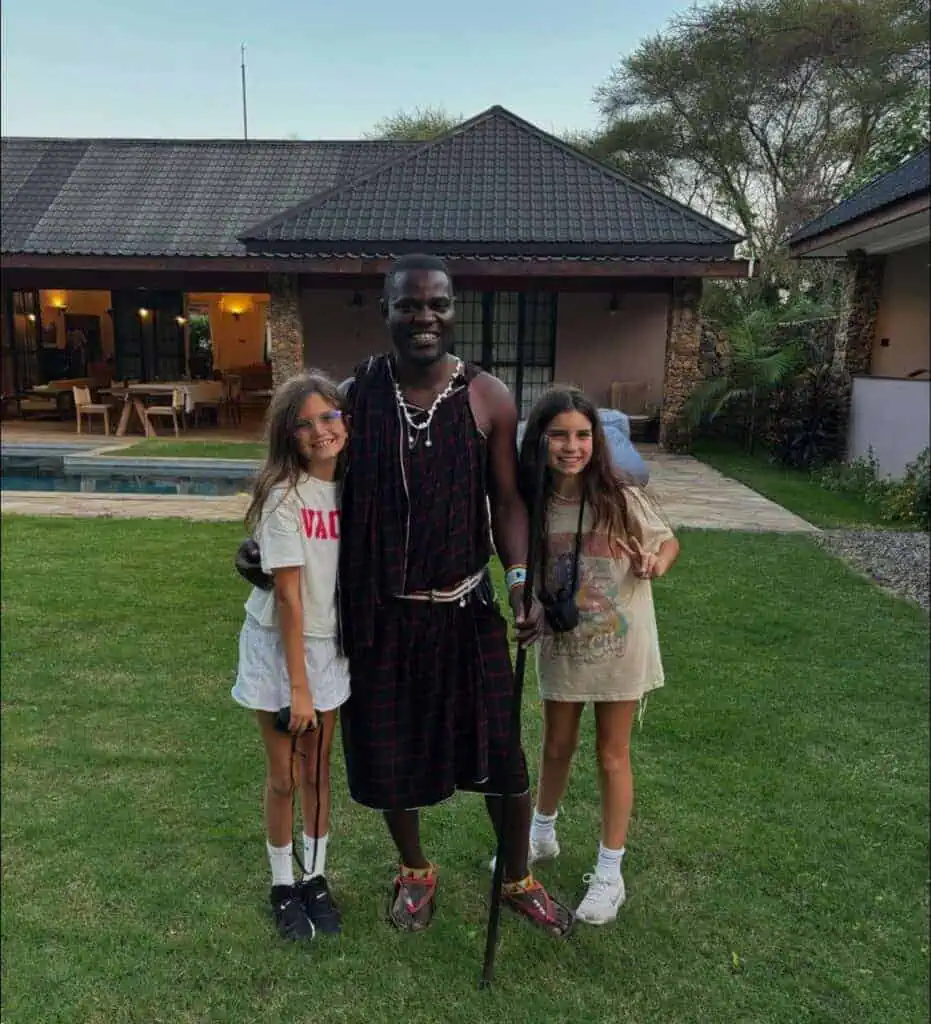 Africa safari guide with children outside luxury lodge in kenya, cultural tour, authentic African experience, family safari adventure, travel and tourism in Africa.