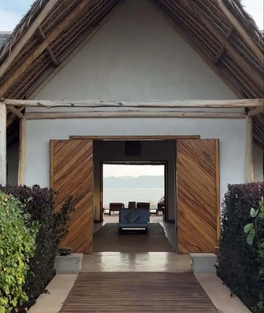 Luxurious African safari lodge with a rustic thatched roof, wooden accents, and stunning views of the surrounding landscape and water body. Perfect for an authentic and comfortable safari experience.