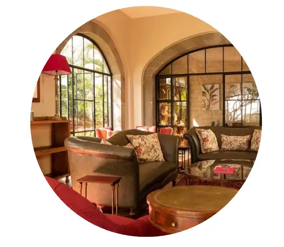 Elegant lounge with large arched windows, comfortable sofas, and vibrant cushions, offering a relaxing atmosphere for guests to unwind after safari adventures.