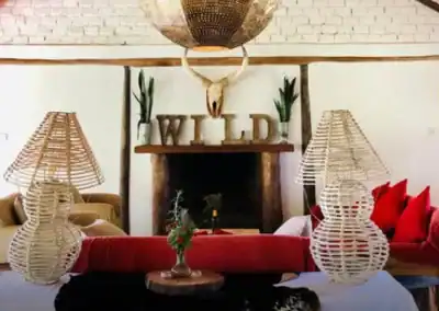A stylish living room featuring a cozy fireplace, decorative "WILD" sign, and unique wicker lamps, creating a warm and inviting atmosphere perfect for relaxing or entertaining guests.