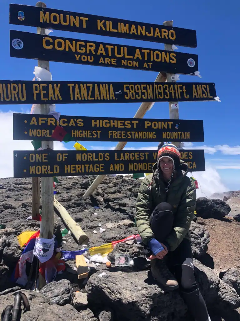 Me sitting beneath the Uhuru Peak sign at the summit of Mount Kilimanjaro