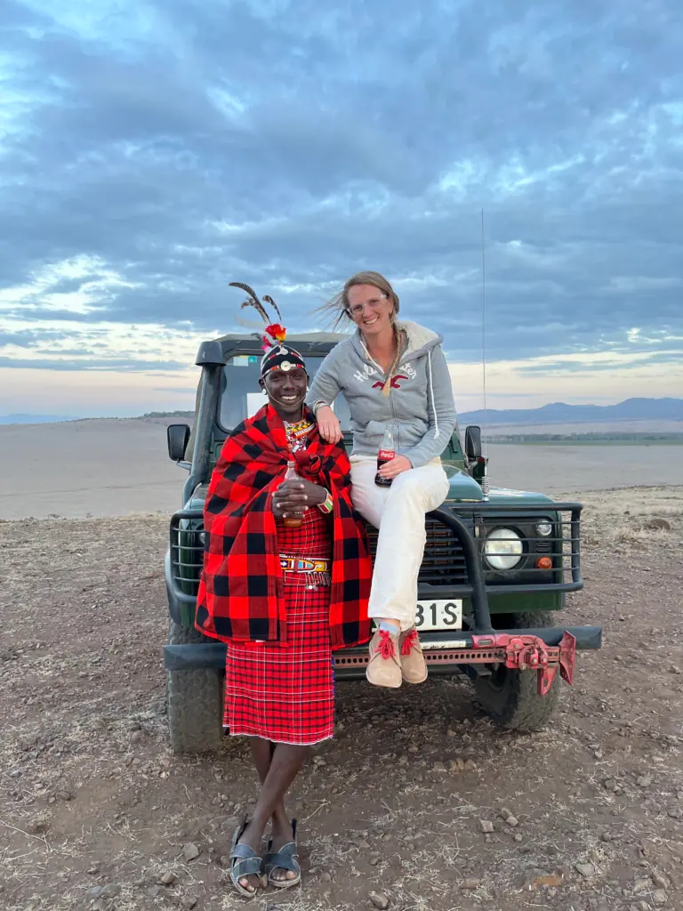 Me sitting on the bonnet of a Land Rover beside a Samburu warrior in a red checked shuka at Lewa Wildlife Conservancy, Kenya