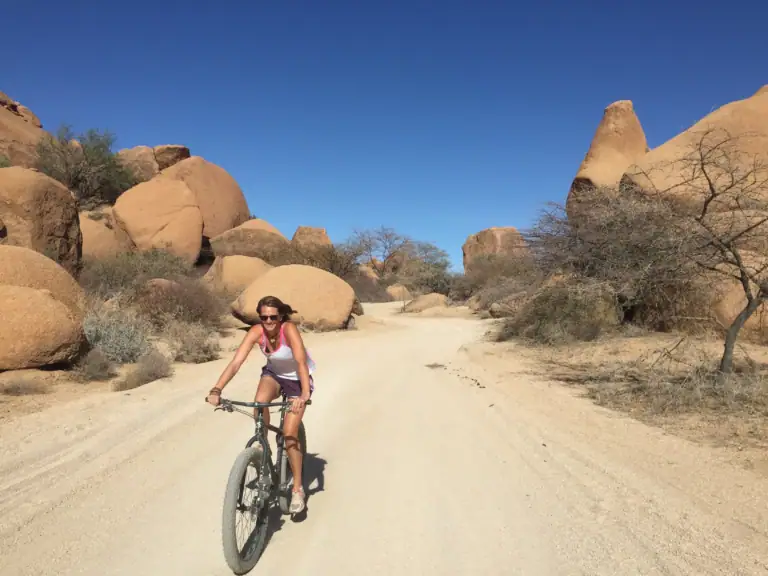 Me cycling along a sandy track between huge granite boulders at Spitzkoppe, Namibia